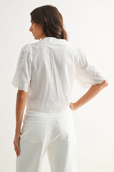 Woman wearing a white blouse and pants against a white background