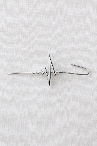 Silver heartbeat ear climber cuff with modern sculptural design displayed on light fabric background, Abeni Ear Climber Cuff by Matte.