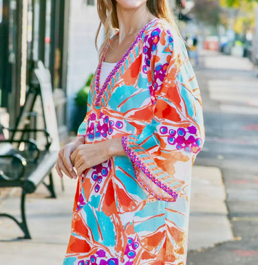 Model wearing Addison Dress with bright tropical print and kimono sleeves.