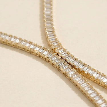 Adele necklace in gold featuring emerald-cut baguette stones in a sleek tennis-style setting on a soft neutral background.