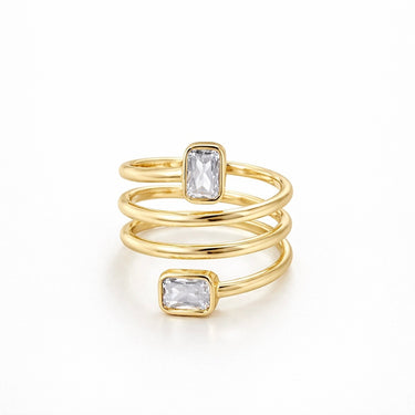 Adonis Ring gold multi band stacked ring with emerald cut clear stones sculptural statement ring on neutral background