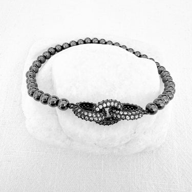 Alrea Stretch Bracelet with metallic beads and crystal centerpiece on white stone background – Matte Jewelry