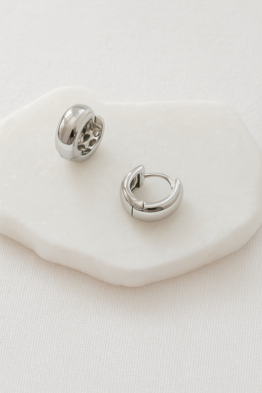 Arden Huggie Earrings — silver mirror-plated rounded huggies on white stone background, sleek and minimalist jewelry by Matte.