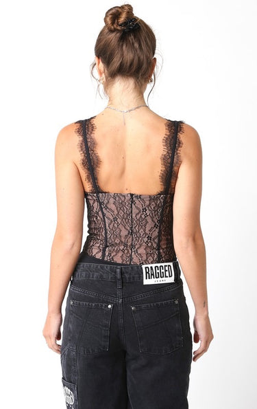 Atta Bodysuit back view showing sheer black lace corset bodysuit with structured shaping and slim straps, styled with black jeans, photographed in studio lighting for full silhouette detail.