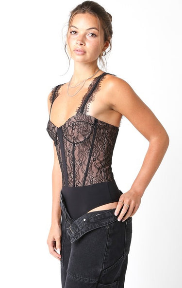Atta Bodysuit sheer black lace corset-inspired bodysuit featuring sculpting boning detail and fitted silhouette, shown from angled front view styled with black denim for a sleek night-out outfit.