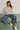 Woman wearing relaxed neutral sweatshirt with dropped shoulders and ribbed cuffs, styled with blue jeans and sneakers.