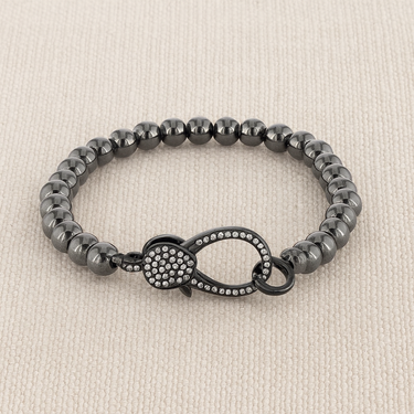 Auria Bracelet — polished hematite beaded bracelet with pavé crystal clasp on linen background, modern jewelry by Matte.