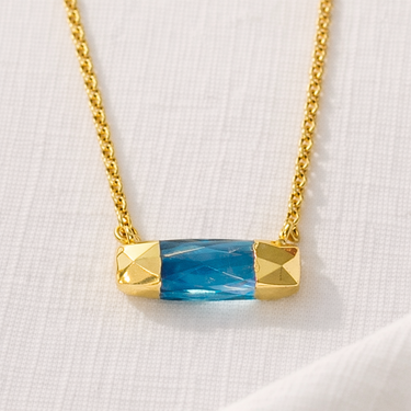 Austin Necklace close-up showing faceted blue bar pendant on gold chain.