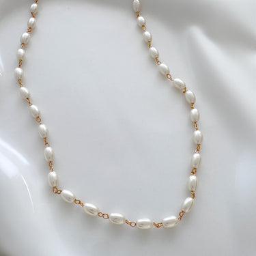 A gold-filled necklace with white pearls, displayed on a white surface.