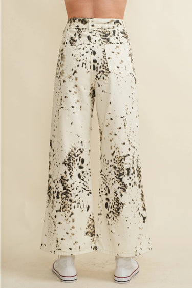Biz Pants back view showing wide-leg relaxed fit and high-rise waistline, ivory base with black abstract print, styled casually with a fitted top and sneakers.