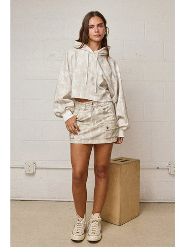 Woman wearing boxy cropped hoodie and matching mini skirt in soft neutral tones, front view.