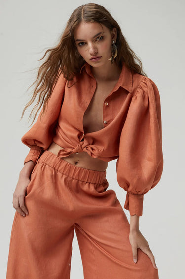 Model wearing Camille Blouse in terracotta organic linen with puff sleeves, close up — Matte Concept Store