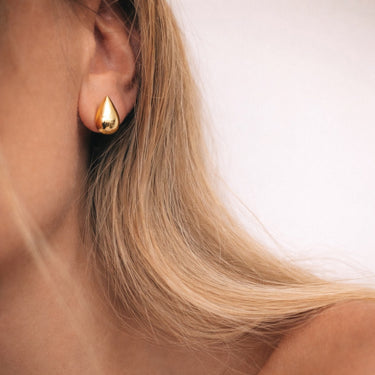 Cleat Stud Earrings gold teardrop stud earrings worn on ear minimal sculptural styling.