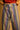 Close-up of Amelti pants showing multicolor stripes, button closure, belt loops and contrast stitching.