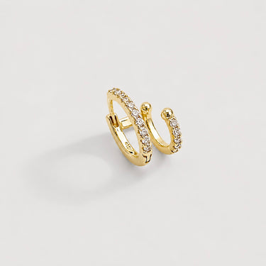 Cuneo Ear Cuff in polished gold with layered double hoops, shimmering crystal pavé stones, and polished bead tips, styled as an elevated no-piercing ear cuff on a soft neutral background.