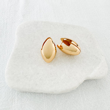 A pair of Doe gold-plated huggie earrings on a white surface