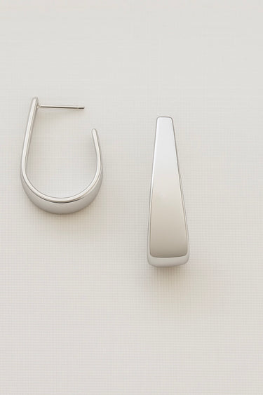 Elera Hoop Earrings — silver sculptural tapered hoop earrings with mirror finish on neutral background, minimalist and elegant jewelry.