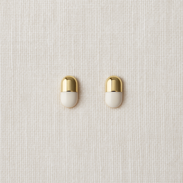 Gold capsule-shaped stud earrings on neutral linen background – Elodie Stud Earrings by Matte