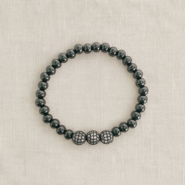 Emera Bracelet — polished hematite beaded bracelet with pavé crystal spheres on linen background, elegant stacking jewelry by Matte.