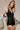 Woman wearing the Ephesus Bodysuit in black with bold metallic embroidery and a fitted V-neck silhouette, photographed in soft natural light on a neutral backdrop.