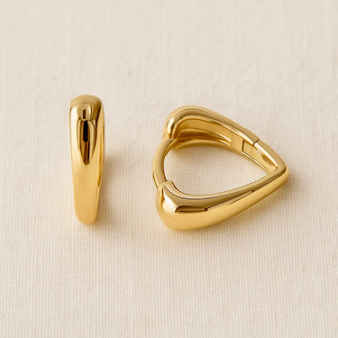 Gold triangular huggie earrings with smooth mirror finish on white linen backdrop, Era Huggie Earrings.