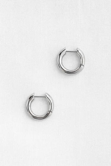 Evoa Huggie Earrings — minimal silver plated huggie earrings with mirror finish on neutral linen background, polished and modern jewelry by Matte.