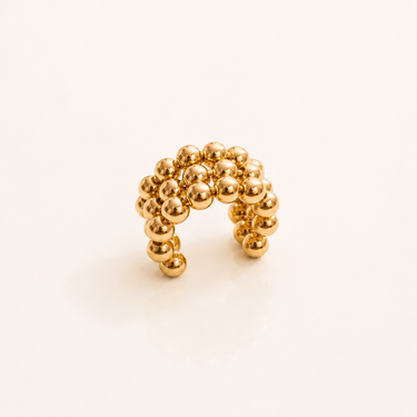 Gaia Beaded Ear Cuff in polished gold featuring layered bubble beads in a sculptural curved silhouette, styled as a modern statement ear cuff with a bold organic design on a soft neutral background.