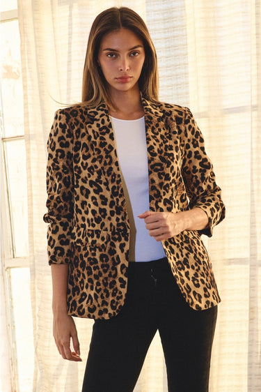 Close-up of women's leopard print blazer featuring structured shoulders, notched lapels, and ruched three-quarter sleeves.
