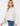 Model wearing the Giselle Blouse in white — semi-sheer, lightweight button-down with voluminous sleeves, styled with denim jeans against a neutral background.