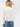 Model wearing the Giselle Blouse in white — semi-sheer, lightweight button-down with voluminous sleeves, styled with denim jeans against a neutral background, back view.