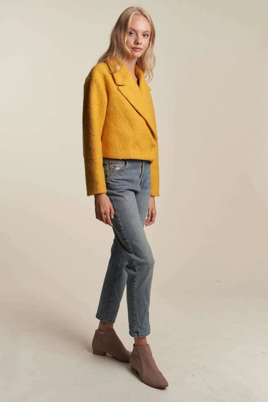 Woman posing in mustard yellow cropped coat with modern tailored style, perfect for fall layering