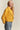 Model wearing mustard cropped coat styled with ankle boots, relaxed casual outfit