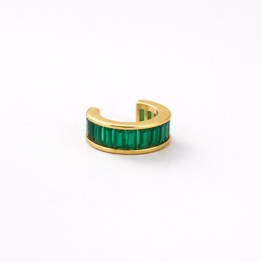 Gold ear cuff with green gemstones on a white background