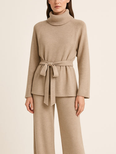 Woman wearing Hailee Lounge Sweater Set in beige, featuring knit turtleneck top with waist tie and wide-leg pants.