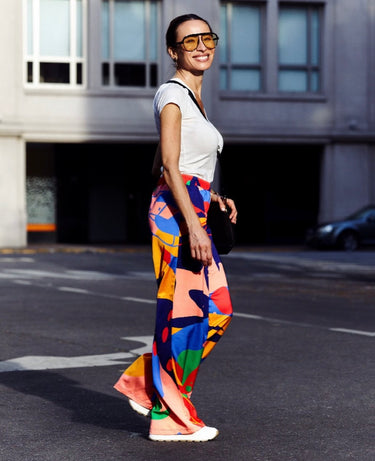 Model wearing multicolor geometric print wide-leg pants with white tee — vibrant resort look.