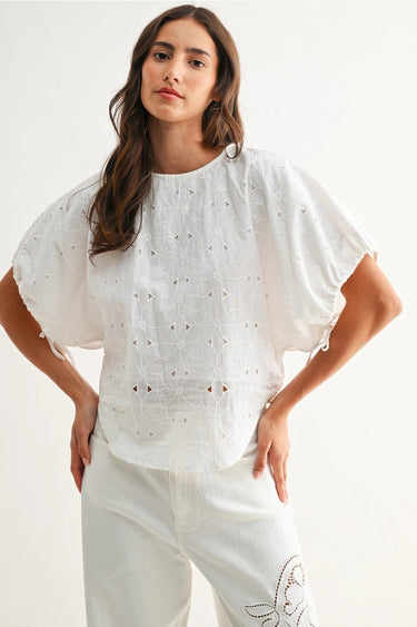 Woman wearing a white blouse with embroidery on a plain background