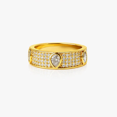 Gold Isola ring with teardrop-shaped diamond on a beige background