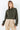Woman wearing the Kairo Blouse in olive green, refined cropped silhouette with pintuck detailing and gold collar charms, photographed on a clean white background.