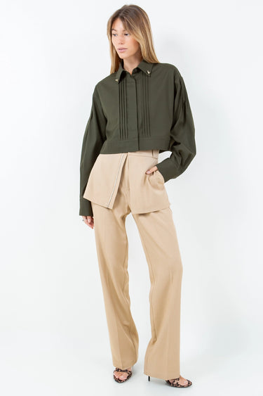 Woman wearing the Kairo Blouse in olive green, refined cropped silhouette with pintuck detailing and gold collar charms, photographed on a clean white background, full outfit.