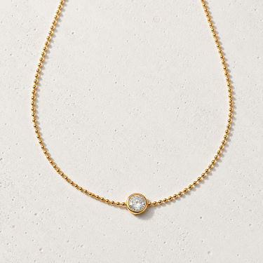 Kopa Necklace featuring a delicate gold-filled chain with a round cubic zirconia solitaire pendant, styled on a light neutral background showcasing its timeless, minimalist design for everyday layering.