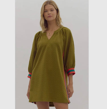Model wearing olive Krewer Dress with colorful side stripes and textured fabric.