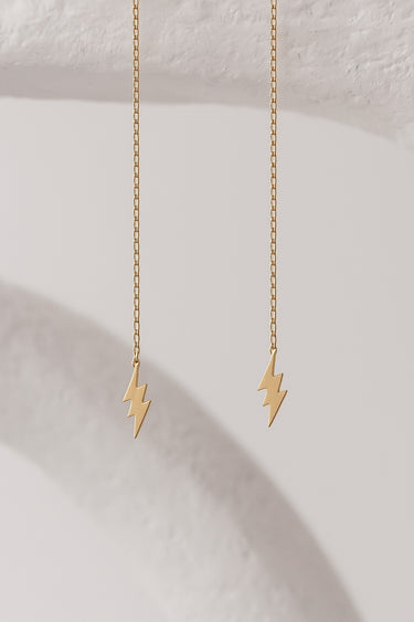 Gold lightning bolt Lirien earrings on a light background