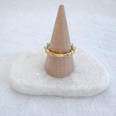 Textured bamboo-inspired ring in gold tones displayed on marble stone – Lisa Ring by Matte.