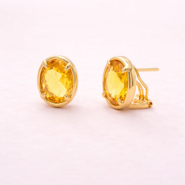 Livona Stud Earrings gold stud earrings with oval yellow zirconia stone in smooth bezel setting on light neutral background.