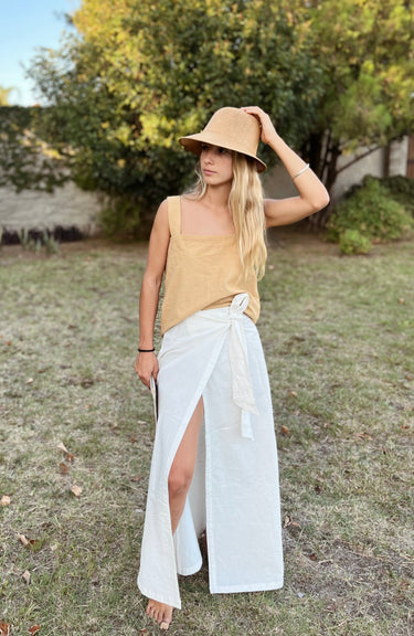 Luli Linen Tank Top mustard sleeveless linen top styled with a white skirt, outdoors full front view.