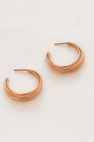 Luzia Hoop Earrings — layered gold plated hoops with modern curved design on beige linen background, polished and elegant jewelry by Matte.