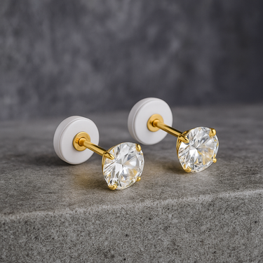 Gold 4 mm stud earrings with round cubic zirconia on a neutral stone background – Maelle Stud Earrings by Matte