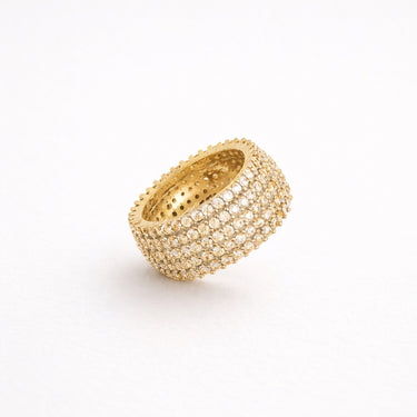 Malawi Ring gold wide pavé band ring fully encrusted with shimmering stones bold chunky statement ring on neutral background.