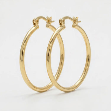 Slim polished gold hoop earrings with a sleek lightweight design and secure hinge closure on a soft neutral background - Matte Jewelry