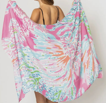 Woman wearing Maranola Sarong in pink tropical print, draped as a beach wrap over swimwear.